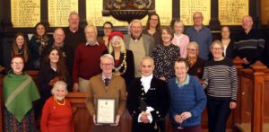 Daryl Chambers holding his award in the Town Hall alongside the High Sheriff, Honorary Townspeople, staff and councillors.