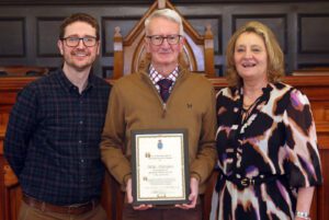 Daryl Chambers holding his award, alongside son Matthew and wife Jilly. They are standing in the Town Hall.